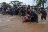 Personel TNI membantu warga mendorong motor yang mogok saat melintasi banjir di kawasan wisata Kraton Surosowan, Kasemen, Kota Serang, Banten, Selasa (1/3/2022). Banjir di 22 titik yang terdapat di 4 kecamatan tersebut terjadi setelah hujan lebat sejak Senin (28/2) dan dilaporkan sebanyak dua orang meninggal dunia, ratusan warga mengungsi serta puluhan rumah rusak. ANTARA FOTO/Asep Fathulrahman/rwa.