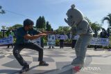 Aktivis dari yayasan HAKA berkolaborasi dengan seniman dan mahasiswa menggelar teatrikal menarik badut badak aksi peduli satwa di Banda Aceh, Aceh, Jumat (4/3/2022). Aksi kreatif tersebut merupakan kampanye menyuarakan pelestarian  satwa dan mendesak pemerintah serius memberantas pelaku kejahatan perdagangan  ilegal satwa dilindungi di Aceh. ANTARA FOTO/Ampelsa