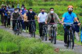 Menteri Pariwisata dan Ekonomi Kreatif (Menparekraf) Sandiaga Salahuddin Uno (kanan) bersepeda di area pesawahan saat sosialisasi Anugerah Desa Wisata Indonesia 2022 di desa Wisata Bantaragung, Majalengka, Jawa Barat, Minggu (6/3/2022). Anugerah Desa Wisata Indonesia 2022 yang ditargetkan diikuti 3.000 desa wisata di seluruh Indonesia tersebut diharapkan dapat mendorong terciptanya destinasi pariwisata berkelas dunia, berdaya saing dan berkelanjutan serta meningkatkan sektor perekonomian desa setempat. ANTARA FOTO/Dedhez Anggara/agr