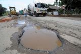 Sejumlah kendaraan melaju pelan saat melintasi Jalan Lintas Sumatera yang rusak di Mestong, Muarojambi, Jambi, Senin (7/3/2022). Jalan nasional penghubung Jambi dengan Sumatera Selatan tersebut rusak di sejumlah titik sehingga membahayakan keselamatan pengendara. ANTARA FOTO/Wahdi Septiawan/rwa.