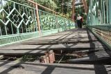 Warga berjalan melintasi jembatan yang berlubang di Jembatan Wiratman, Srengseng Sawah, Jakarta, Sabtu (12/3/2022). Jembatan yang menghubungkan Kelurahan Srengseng Sawah, Jakarta Selatan dengan Kelurahan Pasir Gunung Selatan, Depok tersebut mengalami kerusakan pada papan pijak yang mulai berlubang serta besi yang berkarat sehingga dapat membahayakan warga yang melintas. ANTARA FOTO/Asprilla Dwi Adha/rwa.