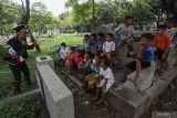 Pendongeng Kak Harris (kiri) mendongeng untuk anak-anak di Makam Simo Kwagean, Surabaya, Jawa Timur, Minggu (20/3/2022). Kegiatan itu untuk memperingati Hari Dongeng Sedunia. Antara Jatim/Didik Suhartono/zk
