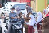 Murid SD bersama para guru di Kota Subulussalam, Aceh, membagikan bunga dan stiker kepada pelintas dalam kampanye stop kekerasan terhadap anak di depan lapangan Beringin, Kota Subulussalam, Selasa (22/3/2022). ANTARA/Fakhrul Razi Anwir