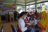 Petugas memeriksa kesehatan warga sebelum divaksinasi COVID-19 dengan latar belakang hadiah di Balai Desa Gebangan, Kapongan, Situbondo, Jawa Timur, Jumat (25/3/2022). Vaksinasi dengan undian berhadiah tersebut bertujuan menarik antusias masyarakat untuk mengikuti vaksinasi COVID-19. Antara Jatim/Seno/zk