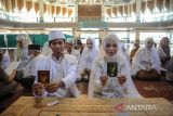 Pasangan pengantin menunjukan buku nikah saat mengikuti nikah massal di Masjid Al Ukhuwah, Bandung, Jawa Barat, Kamis (31/3/2022).  Jelang bulan suci Ramadan, Masjid Al Ukhuwah bekerja sama dengan pihak swasta menggelar pernikahan massal bagi enam orang pasangan pengantin dengan membebaskan biaya nikah kepada setiap mempelai. ANTARA FOTO/Raisan Farisi/agr