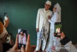 Keluarga memotret pasangan pengantin yang telah menjalani akad saat mengikuti nikah massal di Masjid Al Ukhuwah, Bandung, Jawa Barat, Kamis (31/3/2022). Jelang bulan suci Ramadan, Masjid Al Ukhuwah bekerja sama dengan pihak swasta menggelar pernikahan massal bagi enam orang pasangan pengantin dengan membebaskan biaya nikah kepada setiap mempelai. ANTARA FOTO/Raisan Farisi/agr