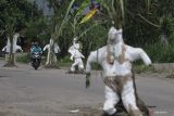 Pengendara sepeda motor melintas di jalan rusak yang ditanami tanaman pisang dan tebu di Desa Janti, Kediri, Jawa Timur, Sabtu (2/4/2022). Warga daerah setempat memberi tanda pada lubang jalan dengan menanam tanaman tebu dan pisang sekaligus memasang baju alat pelindung diri (APD) bekas sebagai bentuk protes karena jalan rusak yang tidak kunjung diperbaiki. Antara Jatim/Prasetia Fauzani/zk