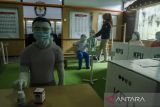 Petugas merapikan masker yang dipasang pada diorama suasana pemungutan suara di TPS saat pemilu di Kantor KPU Jawa Barat, Bandung, Jawa Barat, Kamis (7/4/2022). KPU Jawa Barat memasang masker pada diorama tersebut sebagai edukasi dan sosialisasi dalam pelaksanaan pemilu mendatang apabila di Indonesia masih berada pada status pandemi COVID-19. ANTARA FOTO/Novrian Arbi/agr