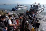 Wisatawan mengantre saat naik ke kapal cepat untuk menyeberang menuju Pulau Nusa Penida saat liburan panjang berkenaan dengan Hari Paskah di Pelabuhan Sanur, Denpasar, Bali, Jumat (15/4/2022). Pihak pelabuhan menyebutkan sejak tiga hari terakhir jumlah wisatawan yang menyeberang ke Pulau Nusa Penida mengalami peningkatan rata-rata 15 persen. ANTARA FOTO/Nyoman Hendra Wibowo/nym.