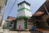 Seorang anak melintas di depan menara masjid Al-Khotib Desa Adan-adan, Kediri, Jawa Timur, Sabtu (16/4/2022). Masjid tua yang memiliki ciri khas menara setinggi 30 meter tempat mengumandangkan adzan tersebut dibangun pada era penjajahan Belanda tahun 1936 oleh penyebar agama Islam KH Muhamad Khotib. Antara Jatim/Prasetia Fauzani/zk