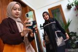 Pengusaha busana muslim sulam Nurul Hidayati (kanan) bersama pekerjanya membuat konten promosi produk melalui media sosial di rumah produksi Almira Handmade, Malang, Jawa Timur, Sabtu (16/4/2022). Pengusaha busana muslim sulam tersebut mengatakan sejak sebulan terakhir penjualan produknya di pasar domestik dan ekspor meningkat dari 250 potong menjadi 500 potong per bulan atau meningkat hingga dua kali lipat. Antara Jatim/Ari Bowo Sucipto/zk