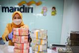 Teller menata tumpukan uang di Kantor Bank Mandiri Cabang Braga, Bandung, Jawa Barat, Senin (18/4/2022). Bank Mandiri Region VI/Jawa 1 menyiapkan kebutuhan uang tunai sekitar Rp6,6 triliun untuk mengantisipasi peningkatan kebutuhan uang tunai masyarakat di Jawa Barat. ANTARA FOTO/Raisan Al Farisi/agr
