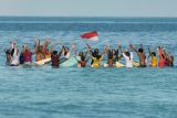 Puluhan peselancar wanita mengenakan pakaian kebaya dan mengibarkan bendera merah putih saat doa bersama di tengah laut di Pantai Kuta, Badung, Bali, Sabtu (16/4/2022). Atraksi selancar untuk menyambut Hari Kartini itu sekaligus sebagai daya tarik wisata guna membangkitkan pariwisata Bali yang terdampak pandemi COVID-19. ANTARA FOTO/Nyoman Hendra Wibowo/rwa.