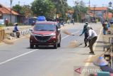 Warga menunggu pengendara motor memberi sedekah dengan melempar uang di Jembatan Sewo, Jalur Pantura Sukra Indramayu, Jawa Barat, Senin (25/4/2022). Aksi mengambil uang sedekah menggunakan sapu tersebut dapat membahayakan keselamatan pengguna jalan terutama saat arus mudik. ANTARA FOTO/Dedhez Anggara/agr
