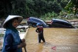 Warga menyaksikan proses evakuasi dua buah mobil yang terseret arus banjir bandang di Citengah, Sumedang Selatan, Kabupaten Sumedang, Jawa Barat, Kamis (5/5/2022). Banjir bandang yang disebabkan luapan Sungai Cihonje akibat hujan deras pada Rabu (4/5/2022) sore tersebut membuat puluhan rumah terdampak, dua kendaraan hanyut dan satu orang korban masih dalam pencarian. ANTARA FOTO/Raisan Al Farisi/agr
