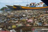 Nelayan menyingkirkan sampah botol plastik bekas bercampur sampah rumah tangga sebelum berangkat melaut di kawasan Pelabuhan Perikanan Lampulo, Banda Aceh, Aceh, Minggu (8/5/2022). Keberadaan sampah botol plastik bekas di pelabuhan perikanan yang bermuara ke perairan pantai itu diduga dibuang pengunjung dan warga tempat selama liburan Idul Fitri 1443 Hijriah  akibat kurangnya kesadaran menjaga lingkungan dan ancaman kerusakan ekosistem laut. ANTARA FOTO/Ampelsa