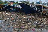 Nelayan bersiap memindahkan kapalnya di lokasi tumpukan sampah botol plastik bekas bercampur sampah rumah tangga di kawasan Pelabuhan Perikanan Lampulo, Banda Aceh, Aceh, Minggu (8/5/2022). Keberadaan sampah botol plastik bekas di pelabuhan perikanan yang bermuara ke perairan pantai itu diduga dibuang pengunjung dan warga tempat selama liburan Idul Fitri 1443 Hijriah  akibat kurangnya kesadaran menjaga lingkungan dan ancaman kerusakan ekosistem laut. ANTARA FOTO/Ampelsa