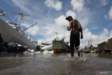 Pekerja berjalan menerjang banjir rob di Pelabuhan Kalimas, Surabaya, Jawa Timur, Rabu (18/5/2022). Sebagian dermaga Pelabuhan Kalimas itu tergenang banjir rob akibat pasang air laut yang tinggi, namun aktivitas bongkar muat di pelabuhan tersebut masih berjalan normal. Antara Jatim/Didik Suhartono