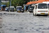 Sejumlah kendaraan bermotor menerjang banjir rob di Jalan Kalimas Baru, Surabaya, Jawa Timur, Rabu (18/5/2022).  Pasang air laut yang tinggi menyebabkan akses jalan menuju Pelabuhan Kalimas dan penyeberangan Ujung (Surabaya)-Kamal (Madura) tersebut terendam banjir rob. Antara Jatim/Didik Suhartono