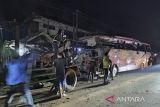 Petugas polisi berjaga jaga di dekat bus Pariwisata yang menabrak rumah warga di Payungsari, Kecamatan  Panumbangan, Kabupaten Ciamis, Jawa Barat, Sabtu (21/5/2022). Sebanyak empat orang tewas dan 24 orang luka-luka dalam kejadian tersebut. ANTARA FOTO/Iyang/ADB/agr