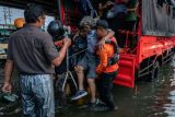 Petugas Basarnas membantu evakuasi warga lanjut usia untuk menembus banjir limpasan air laut ke daratan atau rob yang merendam kawasan Pelabuhan Tanjung Emas Semarang, Jawa Tengah, Senin (23/5/2022). Banjir rob dengan ketinggian bervariasi hingga mencapai 1,5 meter itu disebabkan oleh tingginya pasang air laut serta adanya tanggul yang jebol di kawasan tersebut, sementara itu personel dari Basarnas, TNI-Polri dan relawan diterjunkan untuk membantu evakuasi para pekerja maupun warga. ANTARA FOTO/Aji Styawan/rwa.
