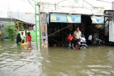 Warga duduk di depan rumahnya yang terendam banjir di Kelurahan Paccinongan, Kecamatan Somba Opu, Kabupaten Gowa, Sulawesi Selatan, Jumat (27/5/2022). Ratusan rumah di daerah itu terendam banjir usai diguyur hujan deras sejak Kamis (26/5/2022) sore. ANTARA FOTO/Arnas Padda/rwa.