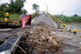 Warga melintas di Jembatan Kacangan yang rusak di Desa Bulurejo, Gresik, Jawa Timur, Kamis (9/6/2022). Jembatan sepanjang 90 meter yang menghubungkan antara Desa Bulurejo dengan Desa Gluranploso itu rusak sejak Desember 2021 dan masih menjadi pilihan utama warga setempat untuk menyebrang meskipun membahayakan keselamatan. ANTARA Jatim/Rizal Hanafi/Zk