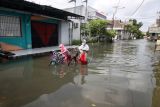 Warga mendorong sepedanya saat menerobos banjir di perumahan kawasan Tropodo, Waru, Sidoarjo, Jawa Timur, Senin (13/6/2022. Curah hujan tinggi dan buruknya drainase mengakibatkan ratusan rumah dikawasan tersebut terendam banjir. ANTARA FOTO/Umarul Faruq/nz