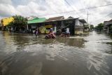 Warga mendorong kendaraannya yang mogok saat mencoba menerobos banjir di perumahan kawasan Tropodo, Waru, Sidoarjo, Jawa Timur, Senin (13/6/2022). Curah hujan tinggi dan buruknya drainase mengakibatkan ratusan rumah dikawasan tersebut terendam banjir. ANTARA FOTO/Umarul Faruq/nz