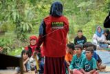 Anggota komunitas Kampung Dongeng Indonesia mendongeng di hadapan anak-anak Taman Baco Atap Rumbe di Jambi Tulo, Muarojambi, Jambi, Minggu (12/6/2022). Kegiatan yang digagas para pegiat literasi dalam rangka peringatan Hari Lingkungan Hidup Sedunia itu mengangkat tema-tema penyelamatan lingkungan sebagai upaya edukasi sejak dini. ANTARA FOTO/Wahdi Septiawan/YU