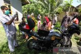 Petugas layanan motor vaksinasi COVID-19 Bhabinkamtibmas Polsek Syamtalira Baru memeriksa kesehatan warga yang akan melakukan vaksinasi COVID-19 di Desa Glong, Aceh Utara, Aceh, Senin (13/6/2022). Polsek di jajaran Polres Lhokseumawe meluncurkan layanan jemput bola vaksinasi COVID-19 dengan sepeda motor ke desa-desa pedalaman yang tidak dapat dilalui kendaraan roda empat guna memberikan kemudahan kepada warga yang kesulitan mendatangi lokasi vaksinasi sekaligus untuk mendorong percepatan capaian vaksinasi COVID-19. ANTARA FOTO/Rahmad