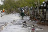 Warga berjalan di depan lapak pedagang yang sudah tidak ditempati akibat abrasi di pantai Karangsong, Indramayu, Jawa Barat, Selasa (14/6/2022). Abrasi pantai di objek wisata tersebut terjadi akibat banjir rob di beberapa pekan terakhir dan menyebabkan kerusakan bibir pantai dan kerusakan lapak milik pedagang. ANTARA FOTO/Dedhez Anggara/agr
