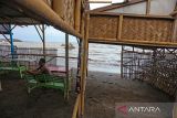 Warga duduk di warung miliknya yang rusak akibat abrasi di pantai Karangsong, Indramayu, Jawa Barat, Selasa (14/6/2022). Abrasi pantai di objek wisata tersebut terjadi akibat banjir rob di beberapa pekan terakhir dan menyebabkan kerusakan bibir pantai dan kerusakan lapak milik pedagang. ANTARA FOTO/Dedhez Anggara/agr
