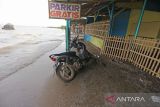 Sebuah motor terparkir di depan lapak pedagang yang sudah tidak ditempati akibat abrasi di pantai Karangsong, Indramayu, Jawa Barat, Selasa (14/6/2022). Abrasi pantai di objek wisata tersebut terjadi akibat banjir rob di beberapa pekan terakhir dan menyebabkan kerusakan bibir pantai dan kerusakan lapak milik pedagang. ANTARA FOTO/Dedhez Anggara/agr
