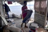 Seorang pria mengumpulkan pakaian di rumahnya yang terdampak abrasi di pesisir pantai Amurang, Minahasa Selatan, Sulawesi Utara, Kamis (16/6/2022). Pemerintah setempat mengeluarkan imbauan evakuasi pada warga yang bermukim di sekitar lokasi terdampak untuk mengantisipasi adanya potensi korban jiwa bila terjadi abrasi susulan. ANTARA FOTO/Adwit B Pramono/nym.