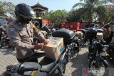 Polisi menata bantuan paket sembako di atas sepeda motornya sebelum dibagikan kepada warga di Pura Agung Jagat Karana, Surabaya, Jawa Timur, Senin (20/6/2022). Pembagian bantuan paket sembako oleh kepolisian kepada masyarakat yang membutuhkan tersebut dalam rangka menyambut HUT ke-76 Bhayangkara. ANTARA Jatim/Didik Suhartono/zk