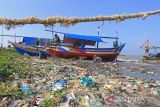 Nelayan memperbaiki perahu di sekitar pantai yang dipenuhi sampah plastik di Juntinyuat, Indramayu, Jawa Barat, Rabu (22/6/2022). Pemerintah Indonesia berkomitmen untuk mengurangi sampah plastik di laut dengan diterbitkannya Rencana Aksi Nasional Penanganan Sampah Plastik Laut dan menargetkan pengurangan sebesar 70 persen di tahun 2025. ANTARA FOTO/Dedhez Anggara/agr
