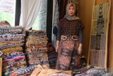 Norayani berpose di antara tumpukan koleksi kain tenun miliknya di Malang, Jawa Timur, Rabu (6/5/2022). Norayani mengatakan sejak tahun 2017 hingga sekarang ia telah mengumpulkan sekitar 700 lembar kain tenun dari seluruh wilayah Indonesia dengan nilai total miliaran rupiah karena menyukai keunikan motif, warna dan nilai historisnya. ANTARA Jatim/Ari Bowo Sucipto/zk