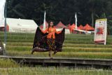 Seorang model mengenakan busana dari bahan batik Cibuluh saat peragaan busana di tengah persawahan di kampung tematik Agro Eduwisata Organik Mulyaharja, Kota Bogor, Jawa Barat, Selasa (5/7/2022). Peragaan busana yang menampilkan koleksi busana batik Cibuluh dan kain perca hasil rancangan sepuluh desainer Kota Bogor tersebut selain dalam rangka Mulyaharja Festival 2022 sekaligus untuk mempromosikan produk busana lokal. ANTARA FOTO/Arif Firmansyah/aww.