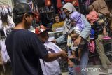 Pembeli mencoba memakai seragam sekolah kepada anaknya di Pasar Manis, Kabupaten Ciamis, Jawa Barat,  Kamis (7/7/2022). Menjelang tahun ajaran baru para orang tua berbelanja kelengkapan sekolah seperti buku, baju seragam, dan sepatu. ANTARA FOTO/Adeng Bustomi/agr
