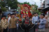 Warga Suku Osing mengarak pengantin menggunakan dokar (delman) di Desa Kemiren, Banyuwangi, Jawa Timur, Kamis (14/7/2022). Arak-arakan pengantin yang melibatkan warga dengan berbagai kesenian khas seperti Barong, Macanan, Jaran Kencak dan pitik-pitikan itu merupakan tradisi Suku Osing Kemiren yang hingga saat ini masih dilestarikan. ANTARA Jatim/Budi Candra Setya/zk
