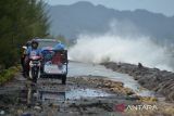 Becak Mesin  melintasi jalan pantai saat berlangsung gelombang tinggi di daerah pesisir Kampung Jawa, Banda Aceh, Aceh, Jumat (15/7/2022). Badan Meteorologi, Klimatologi dan Geofisika (BMKG) memperingatkan kapal nelayan, kapal tongkang, kapal ferry, kapal kargo serta kapal pesiar agar mewaspadai tinggi gelombang 1,25 hingga 2,50 meter di perarian Selat Melaka, sedangkan tinggi gelombang  2,50 hingga 4 meter di perairan Utara Sabang, perarian Barat Aceh, perarian Pulau Simeulue dan Samudera Hindia Barat Aceh hingga kepulauan Nias yang berpeluang terjadi hingga tanggal 17 Juli 2022. ANTARA FOTO/Ampelsa.