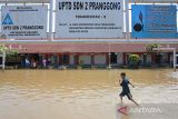 Seorang anak bermain air saat banjir menggenangi SDN 02 Pranggong, Kecamatan Arahan, Indramayu, Jawa Barat, Senin (18/7/2022). Pihak sekolah terpaksa meliburkan siswanya pada hari pertama masuk sekolah karena sejumlah ruang kelas terendam banjir akibat luapan sungai Cipelang. ANTARA FOTO/Dedhez Anggara/agr