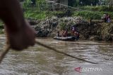 Tim SAR gabungan membantu pelajar menaiki perahu karet untuk menyebrangi Sungai Cimanuk, Garut, Jawa Barat, Selasa (19/7/2022). Warga di kawasan tersebut terpaksa menggunakan perahu karet yang disediakan oleh Tim SAR gabungan Polri, TNI dan Badan Penanggulangan Bencana Daerah (BPBD) Garut untuk akses penyeberangan, khususnya untuk menuju sekolah setelah jembatan penghubung antarkecamatan dampak banjir bandang Sungai Cimanuk beberapa waktu lalu. ANTARA FOTO/Novrian Arbi/agr