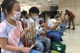 Seorang staf Kedutaan Besar RI di Beijing mengajari cara memainkan alat musik tradisional angklung kepada murid-murid sekolah dasar di Beijing, China, Kamis (21/7/2022). Kegiatan tersebut merupakan bagian dari program pertukaran budaya Indonesia dan China. ANTARA FOTO/M. Irfan Ilmie/tom.