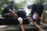 Petugas menggunakan kain milik peziarah untuk membersihkan batu manik di petilasan Sri Aji Jayabaya Desa Menang, Kediri, Jawa Timur, Jumat (29/7/2022). Tradisi membersihkan batu manik di petilasan raja Kediri yang terkenal dengan ramalan masa depan nusantara 'Jangka Jayabaya' tersebut dilakukan menjelang bulan Suro penanggalan Jawa. Antara Jatim/Prasetia Fauzani/zk.