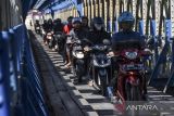 Warga menggunakan kendaraan bermotor melintasi terowongan jembatan Cirahong, di Kabupaten Ciamis, Jawa Barat, Jumat (5/8/2022). Korps Lalu Lintas (Korlantas) Polri akan menerapkan penghapusan data kendaraan yang tidak memperpanjang Surat Tanda Nomor Kendaraan (STNK) selama dua tahun dan dianggap sebagai kendaraan bodong. ANTARA FOTO/Adeng Bustomi/agr