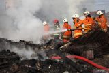 Petugas Dinas Pemadam Kebakaran dan Penyelamatan Kota Surabaya melakukan proses pembasahan tempat usaha pengepulan barang bekas yang terbakar di kawasan Wonoayu, Surabaya, Jawa Timur, Selasa (9/8/2022). Sebanyak 14 kendaraan pemadam kebakaran dikerahkan untuk memadamkan tempat usaha yang terbakar di kawasan padat penduduk tersebut. Antara Jatim/Didik Suhartono/zk.