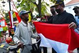 Wali Kota Madiun Maidi (kanan) membagikan bendera merah putih kepada seorang warga di depan Balai Kota Madiun, Jawa Timur, Jumat (12/8/2022). Pemkot Madiun membagikan 5.000 bendera merah putih kepada warga guna memeriahkan Peringatan HUT ke-77 Proklamasi Kemerdekaan RI. ANTARA Jatim/Siswowidodo/ZK