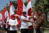 Menteri Dalam Negeri Tito Karnavian (tengah) didampingi Gubernur Jawa Timur Khofifah Indar Parawansa (kiri) menyerahkan Bendera Merah Putih kepada perwakilan warga saat acara Gerakan Nasonal Pembagian 10 Juta Bendera Merah Putih di Gedung Negara Grahadi, Surabaya, Jawa Timur, Minggu (14/8/2022). Kegiatan tersebut merupakan salah satu upaya dalam meningkatkan patriotisme dan nasionalisme masyarakat di seluruh Indonesia. Antara Jatim/Moch Asim/zk.